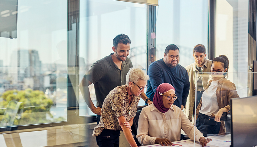 Diverse Group of Adults looks at a computer screen at a table