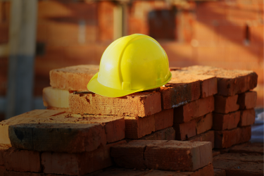 Yellow construction hard hat on stack of bricks