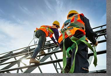 Two construction workers wearing harnesses climbing a scaffold